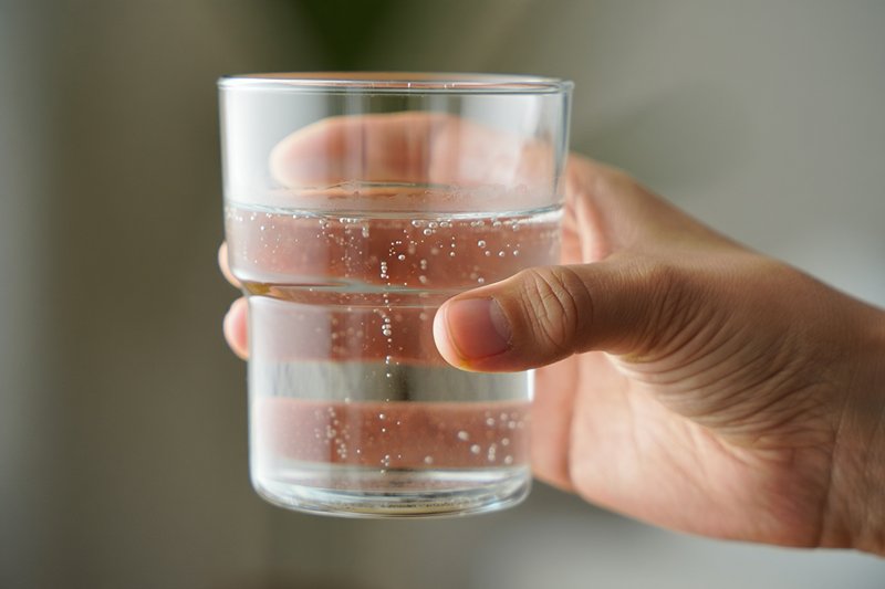 Рука протягивает стакан воды